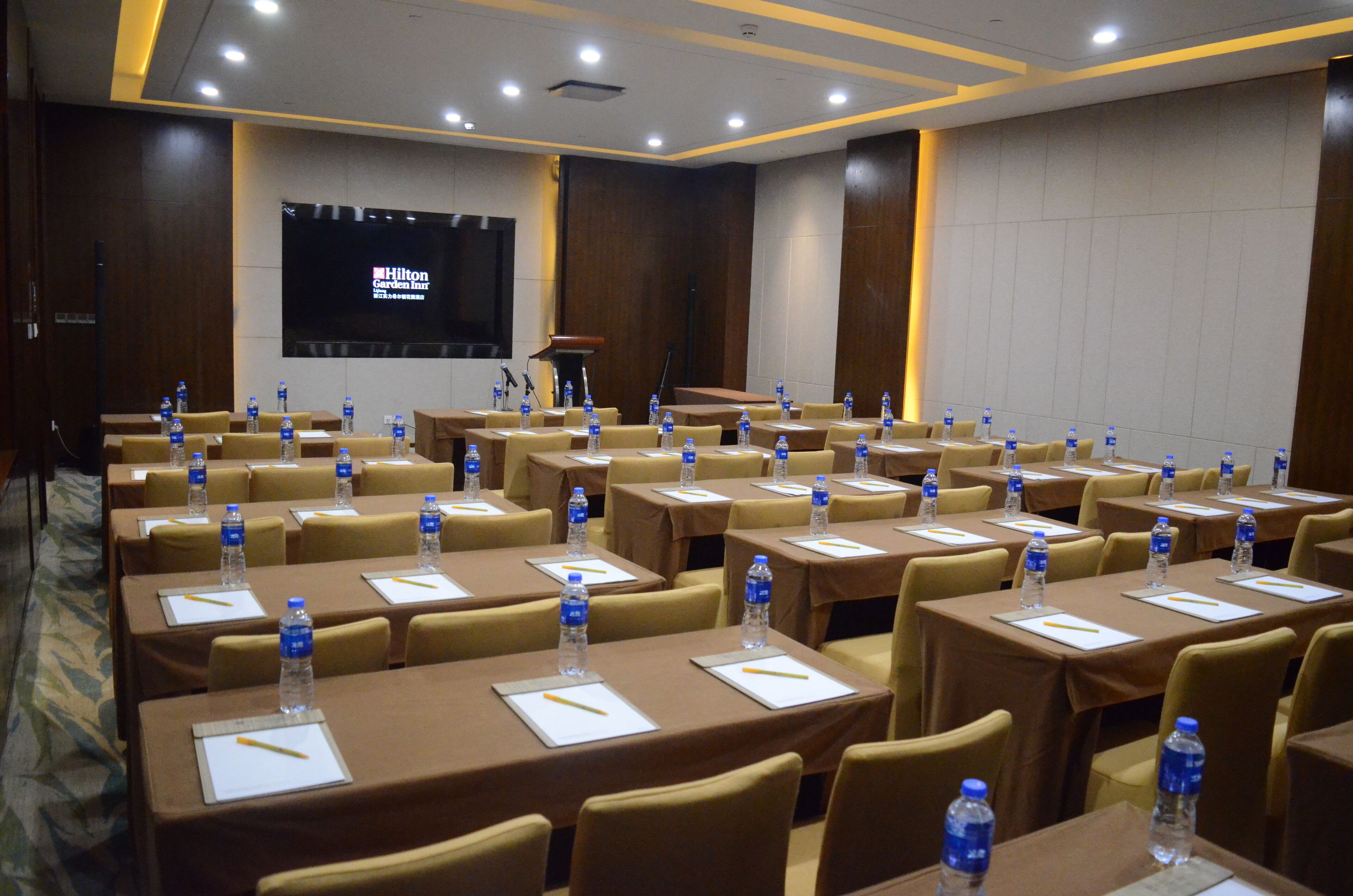 A conference room with tables set up for a meeting, equipped with water bottles and nameplates.