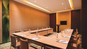 A conference room with a long table, chairs, water bottles, and a podium.
