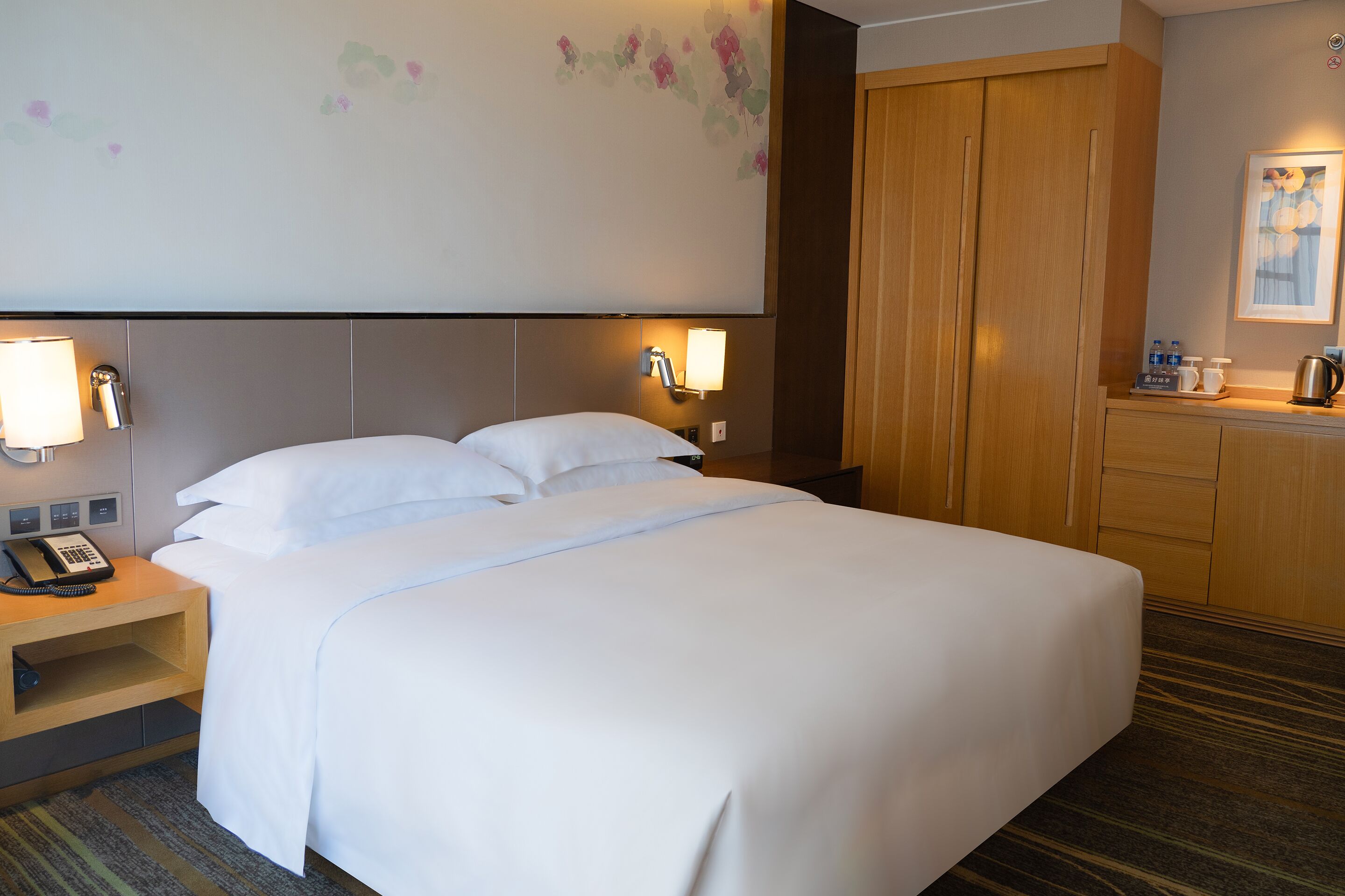 Ein Hotelzimmer mit einem großen Bett, Nachttischlampen, einem Telefon und einem Holzschrank.