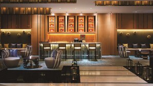 A modern hotel lobby with a bar area, seating arrangements, and a display of bottles. - Hilton Garden Inn Lijiang (Lijiang)