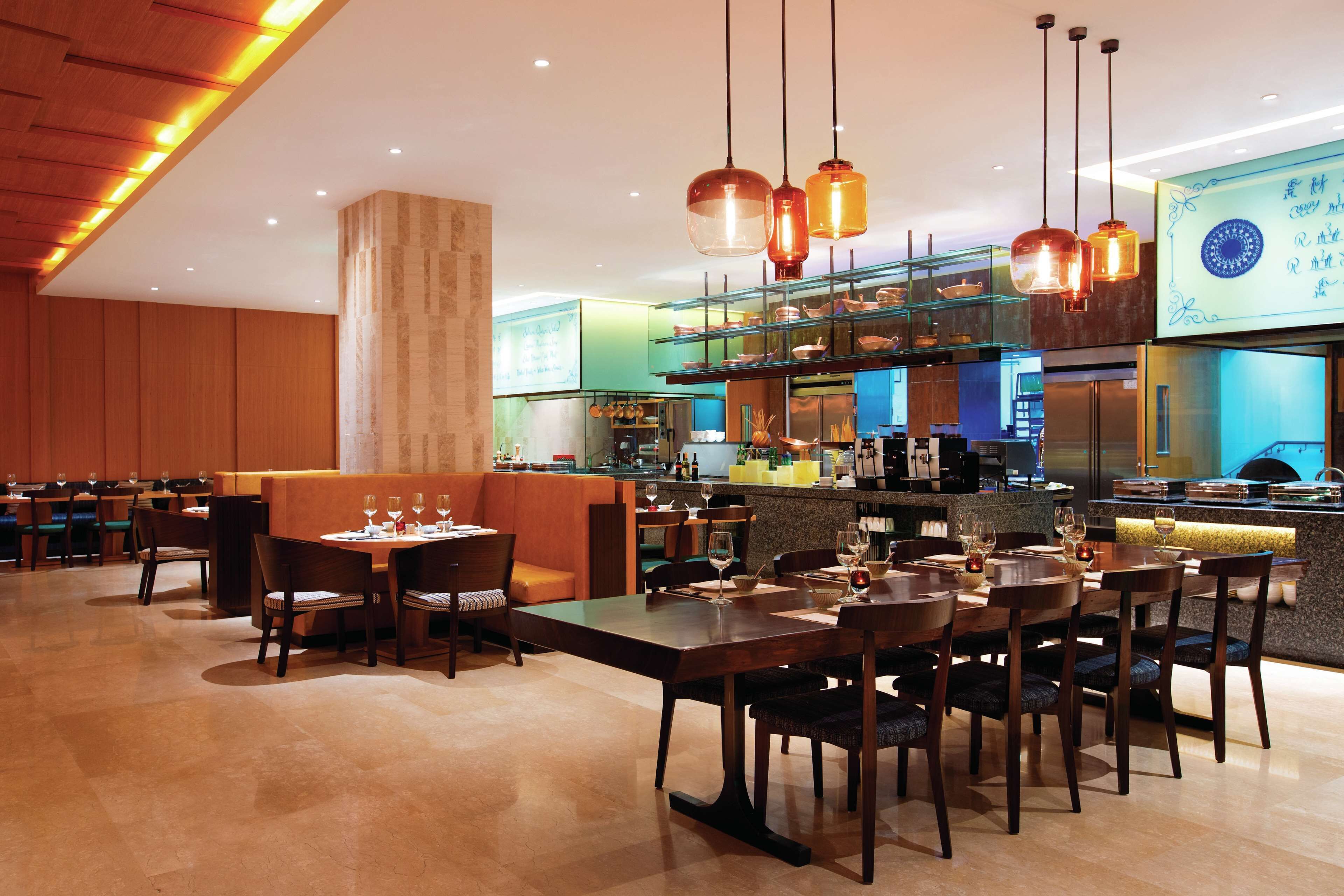 Een restaurant met houten meubels, een bar en hangende kroonluchters.