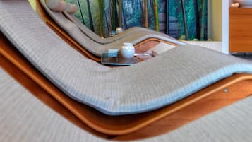 Relax in a serene space with a curved bed, wall-mounted screen, and self-service vanity.
