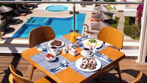 Mesa de comedor con sillas y vistas a una piscina y al mar.