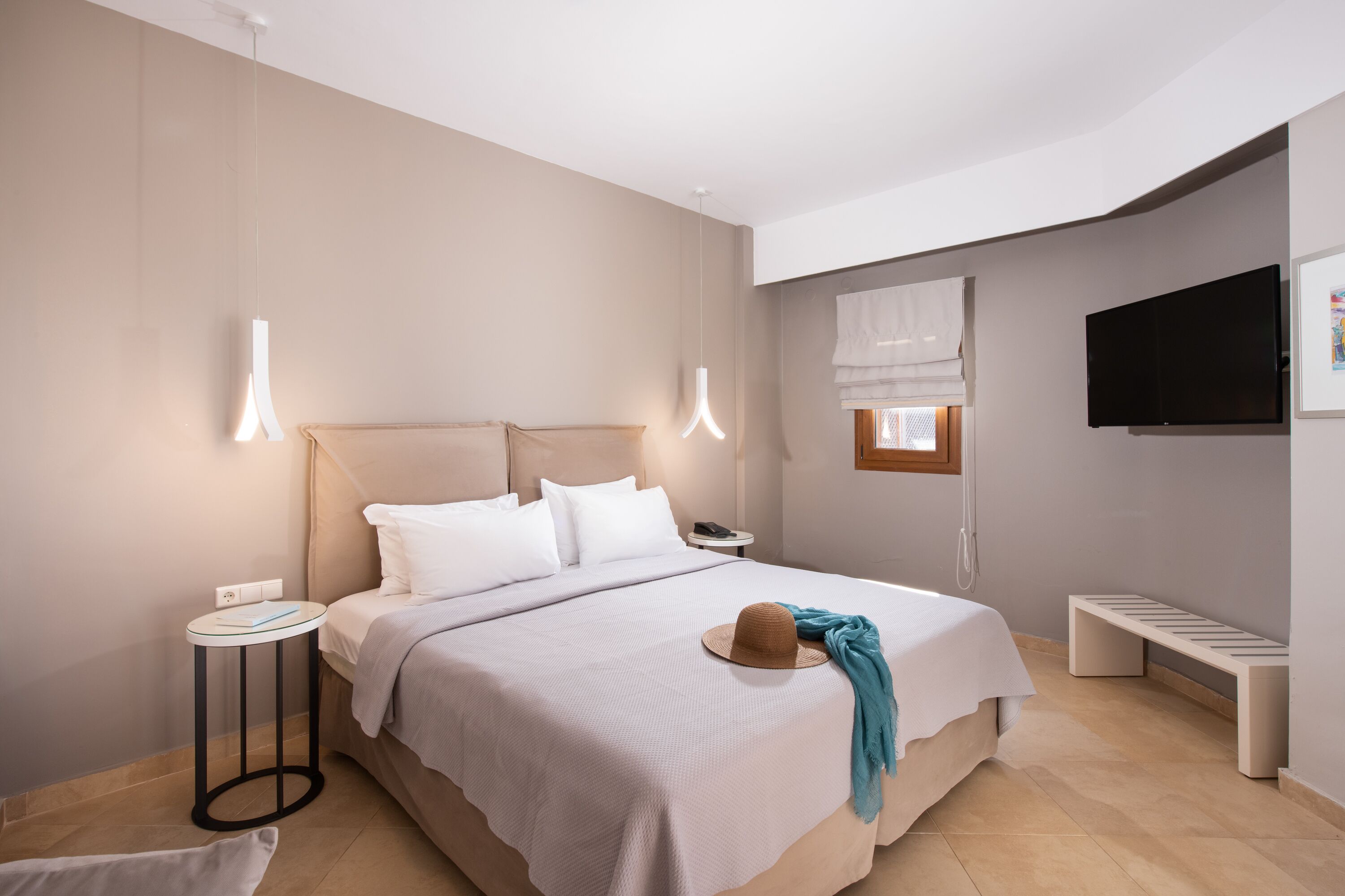 Ett modernt hotellrum med en stor säng, sängbord, en platt-TV och ett fönster med utsikt.
