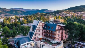 Et hotel med et unikt, vinklet design, flere balkoner og udsigt over en by og bjerge.