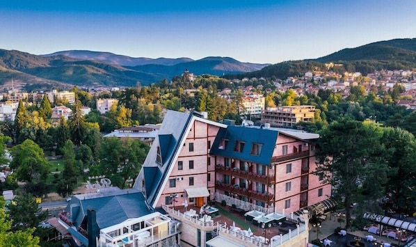 A hotel with a unique angular design, multiple balconies, and a view of a town and mountains. - Spa Hotel Rich (Velingrad)