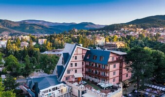 Un hotel con un diseño angular distintivo, varios balcones y vistas a un pueblo y montañas.