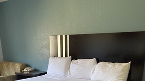 A large bed with white linens, a dark headboard, and a bedside table with a phone. - Travel Inn Abilene (Abilene)