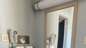 A bathroom with a granite countertop sink, a mirror, and a hairdryer mounted on the wall. - Travel Inn Abilene (Abilene)