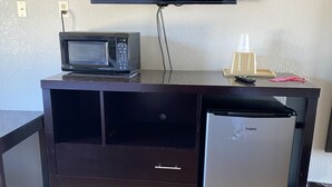 A compact kitchenette with a microwave, refrigerator, and a flat-screen TV mounted on the wall. - Travel Inn Abilene (Abilene)