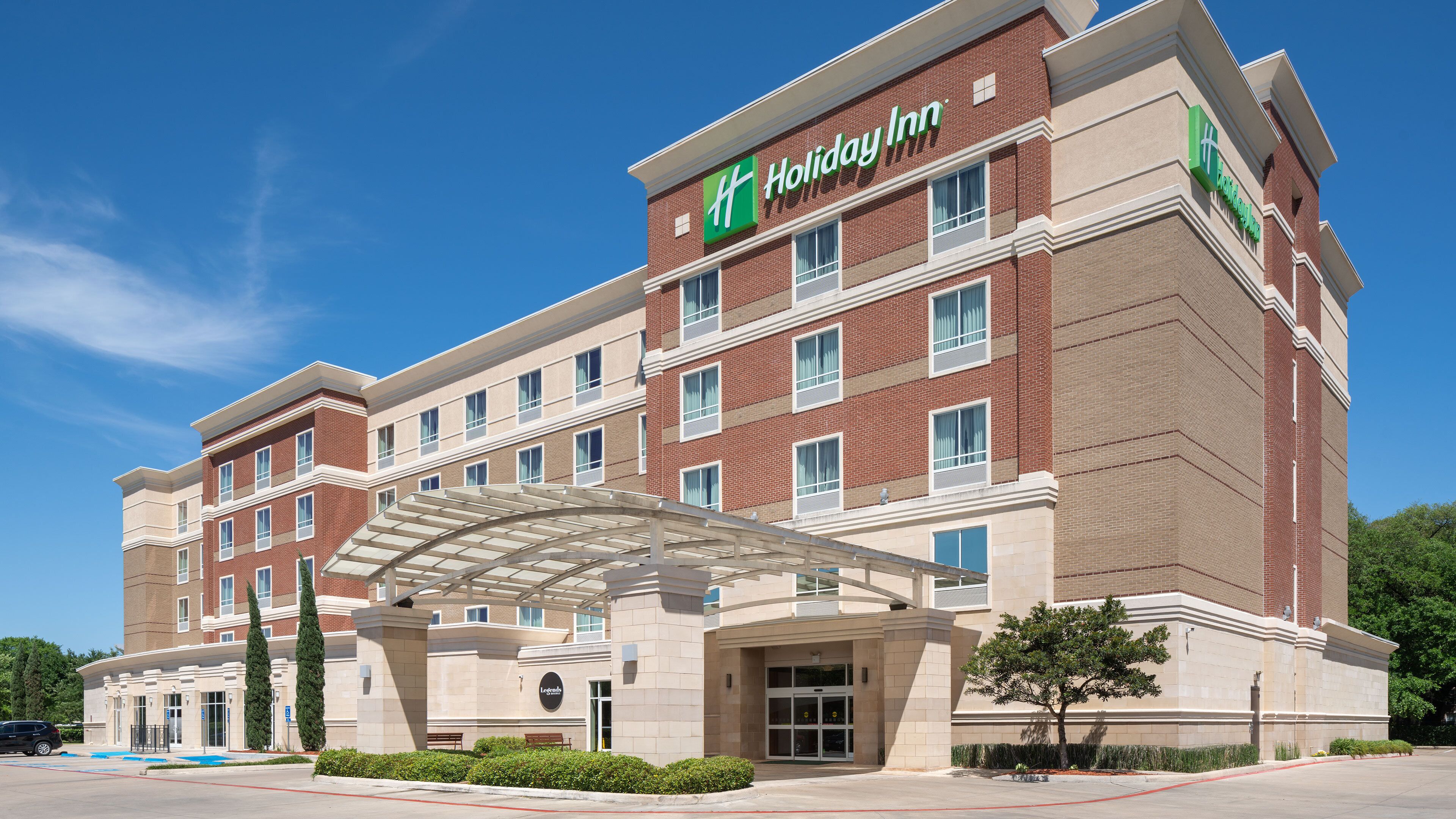 Holiday Inn -hotelli, jossa on tiiliverhous, useita ikkunoita ja katettu sisäänkäynti.