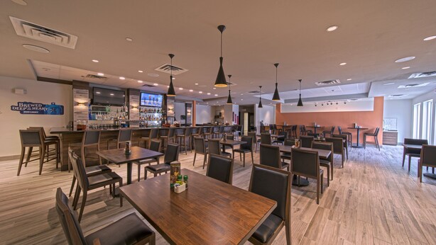 Un restaurant spacieux avec de nombreuses tables et chaises, un bar et un écran de télévision.