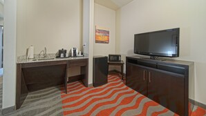 Une chambre d’hôtel compacte équipée d’une kitchenette, d’un téléviseur à écran plat et d’un four à micro-ondes.