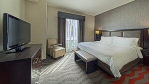 Une chambre d’hôtel avec un grand lit, un téléviseur à écran plat, un bureau et une chaise.