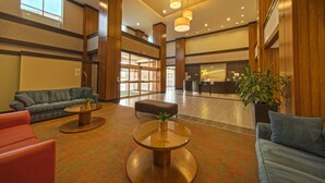 Un hall d’entrée spacieux avec un comptoir d’accueil, des coins salon et une grande plante.