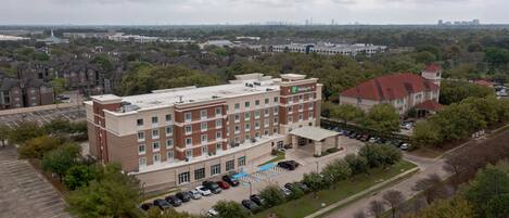 A multi-story hotel with a brick facade, a parking lot, and a view of the surrounding cityscape.