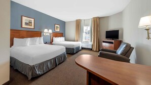 Une chambre d’hôtel avec deux lits, un bureau, une télévision et une fenêtre avec des rideaux.