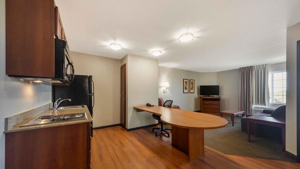 Une chambre d’hôtel compacte comprenant un coin cuisine, un espace repas, une télévision et un coin salon avec vue sur l’extérieur.
