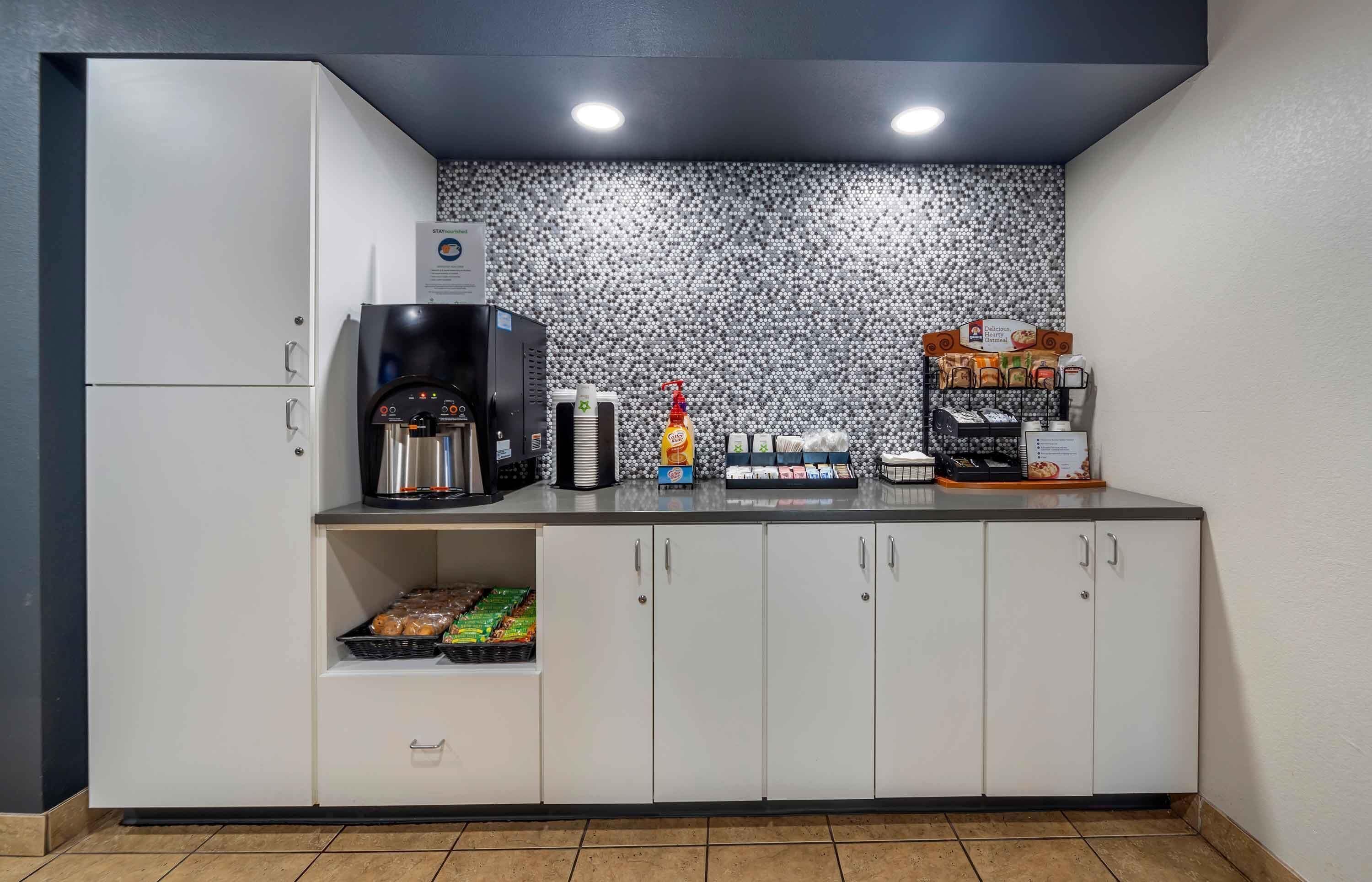 A kitchenette with a coffee maker, condiment dispensers, and a snack shelf.