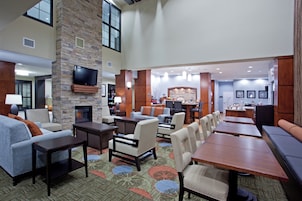 Un hall de hotel con chimenea, zona de estar y televisor montado en una pared de piedra.
