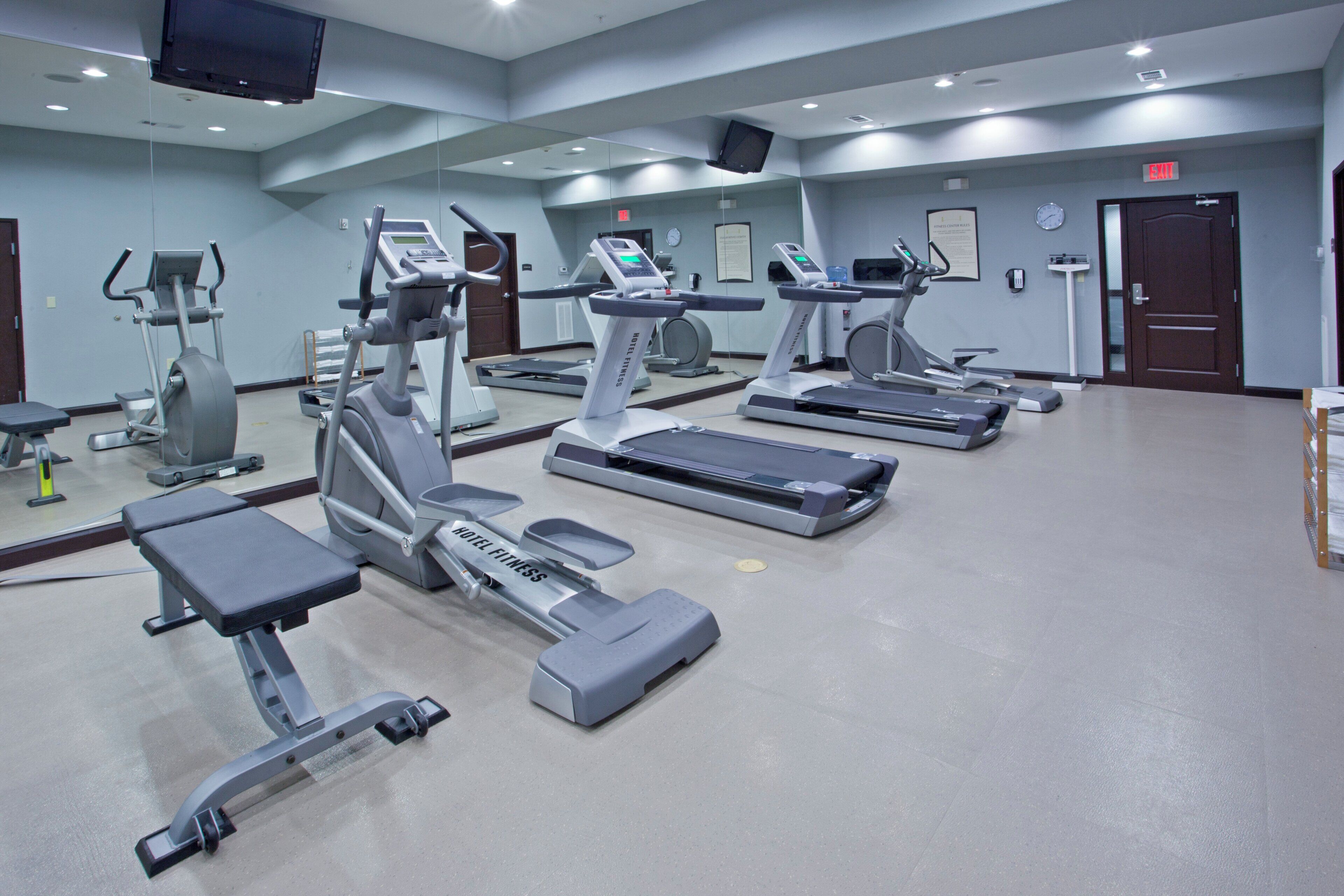 A hotel fitness center with multiple treadmills, stationary bikes, and a weight machine.
