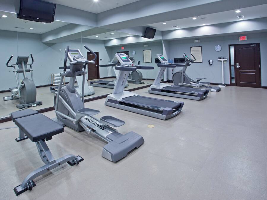 A hotel fitness center with multiple treadmills, stationary bikes, and a weight machine.