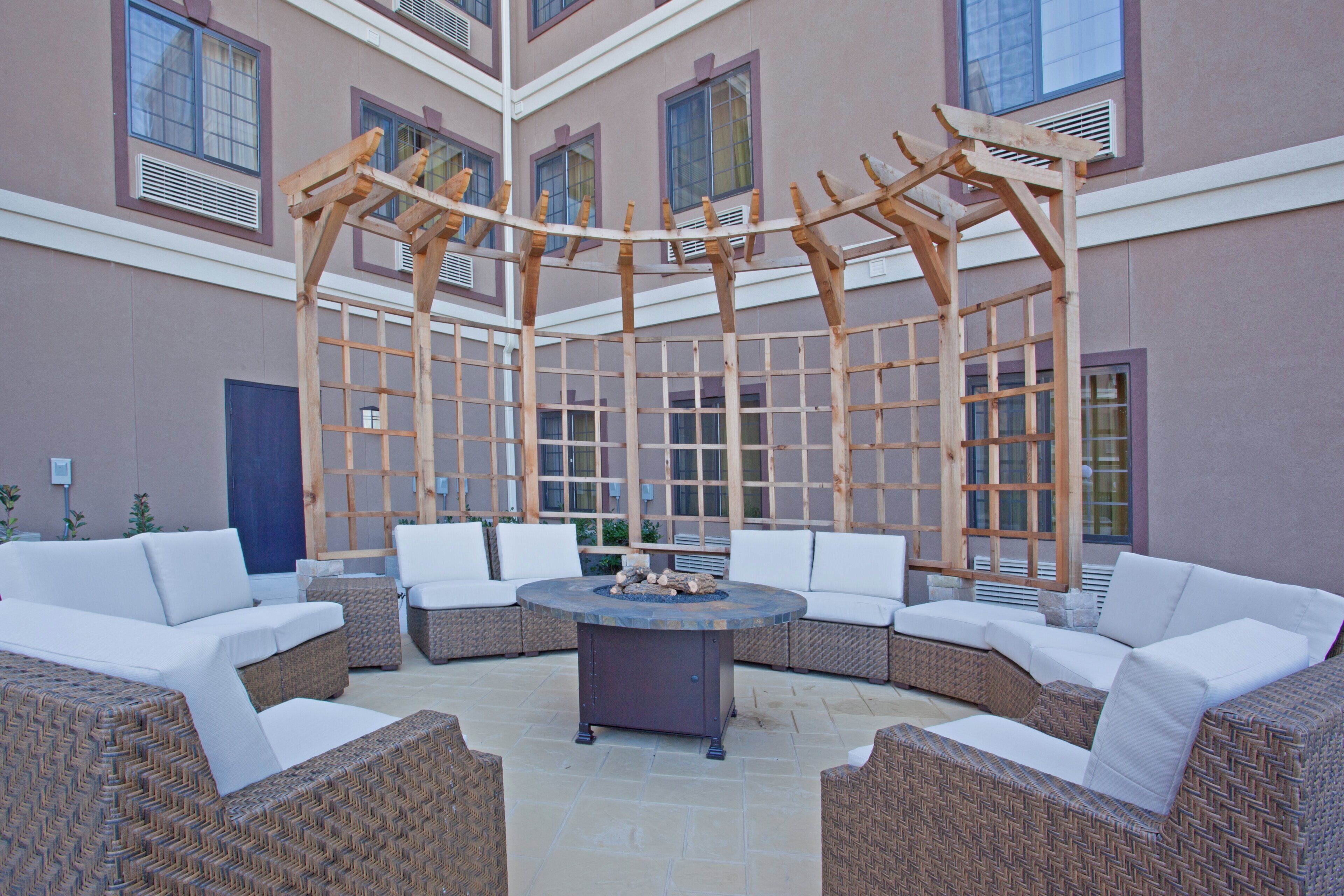 A covered outdoor seating area with wicker furniture and a central fire pit.