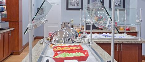 Ein reichhaltiges Buffet mit verschiedenen Speisen, einer Limonadenmaschine und einem Kühlschrank.