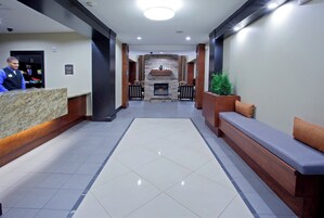 Un vestíbulo de hotel con una recepción, zona de estar y chimenea.