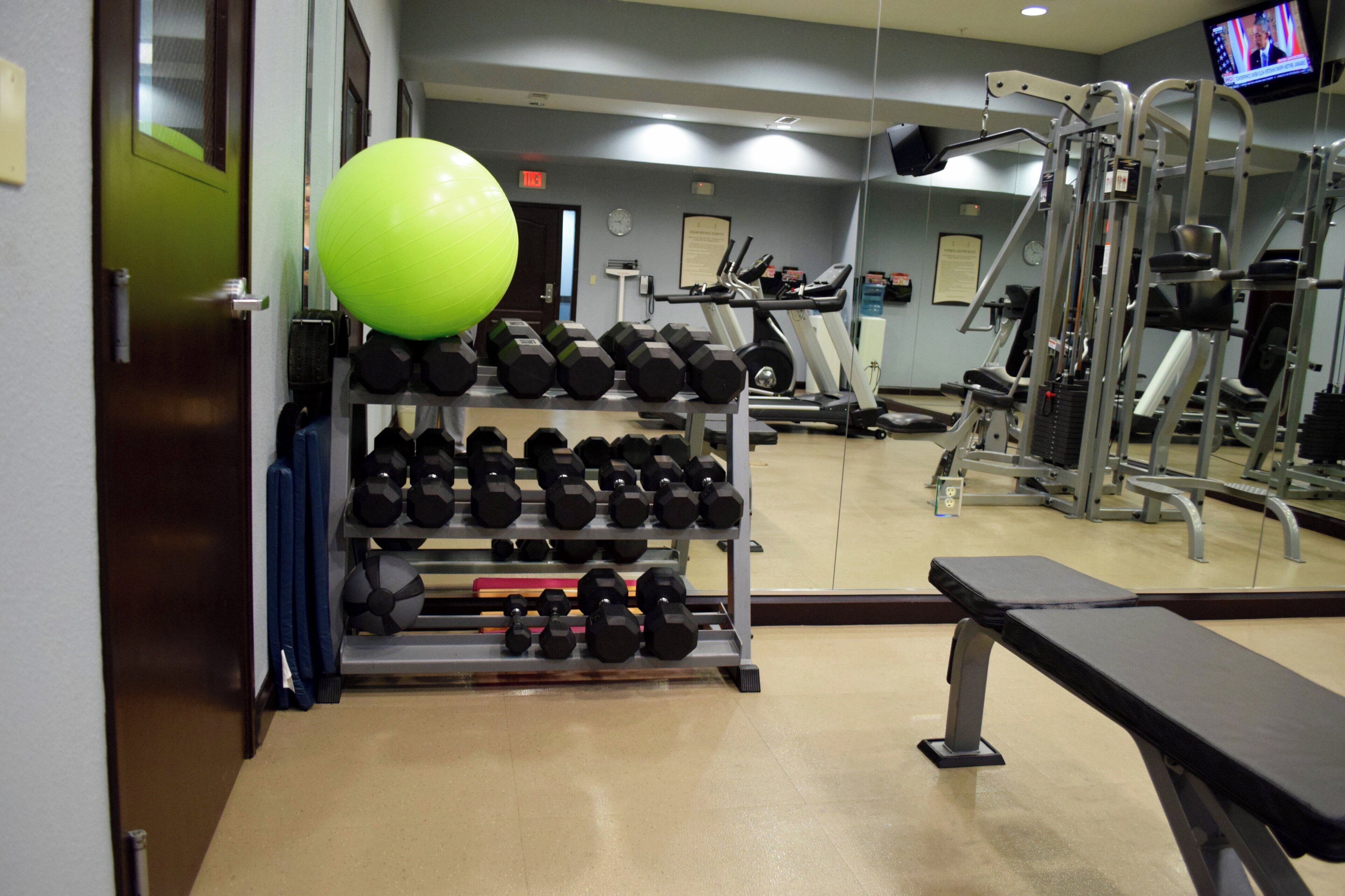 A gym with exercise equipment, a bench, and a television screen.