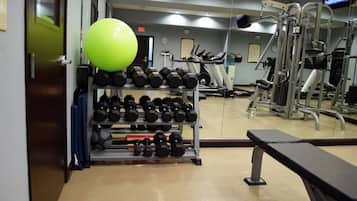 A gym with exercise equipment, a bench, and a television screen.