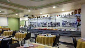 A restaurant with tables set for dining, a counter with food items, and a wall displaying black and white photographs. - Lider Hotel Manaus (Manaus)