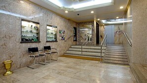 A lobby with marble walls, a reception desk, and a staircase leading to an upper floor. - Lider Hotel Manaus (Manaus)