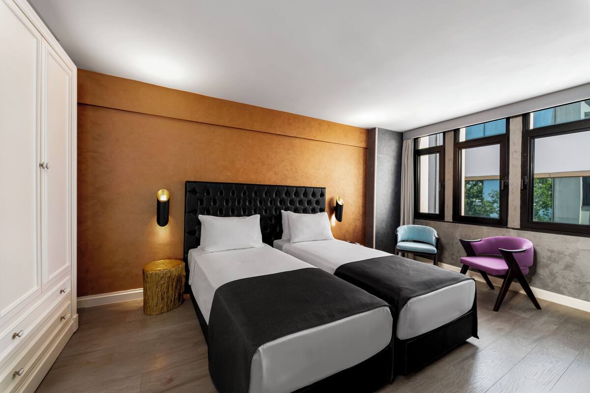 Ein modernes Hotelzimmer mit zwei Betten, einem großen Fenster und Blick ins Freie.