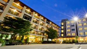 Een meerlaags hotel met balkons, een restaurant en een goed verlichte entree.