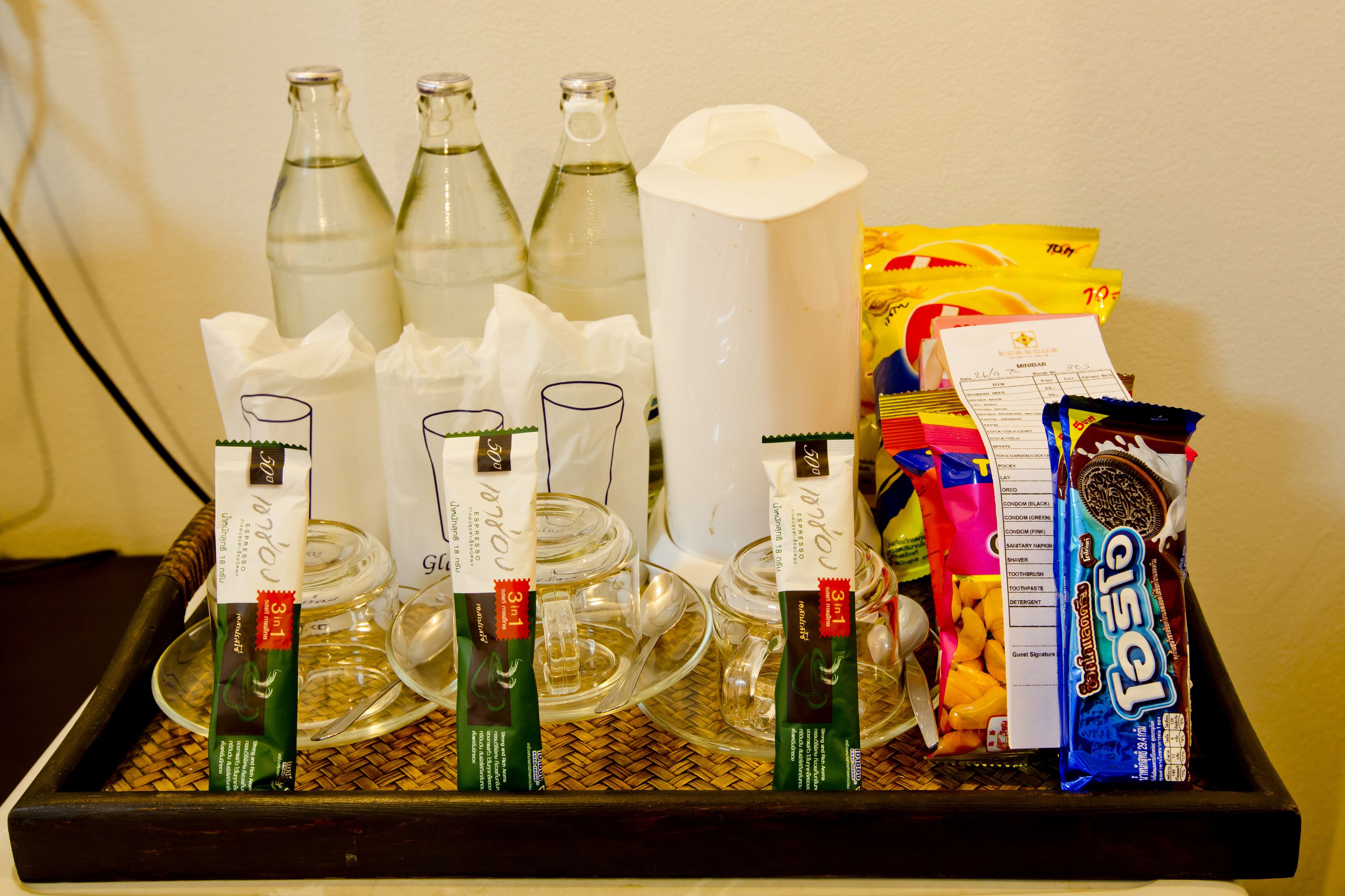 A tray with various items including bottles, glasses, and packaged snacks.