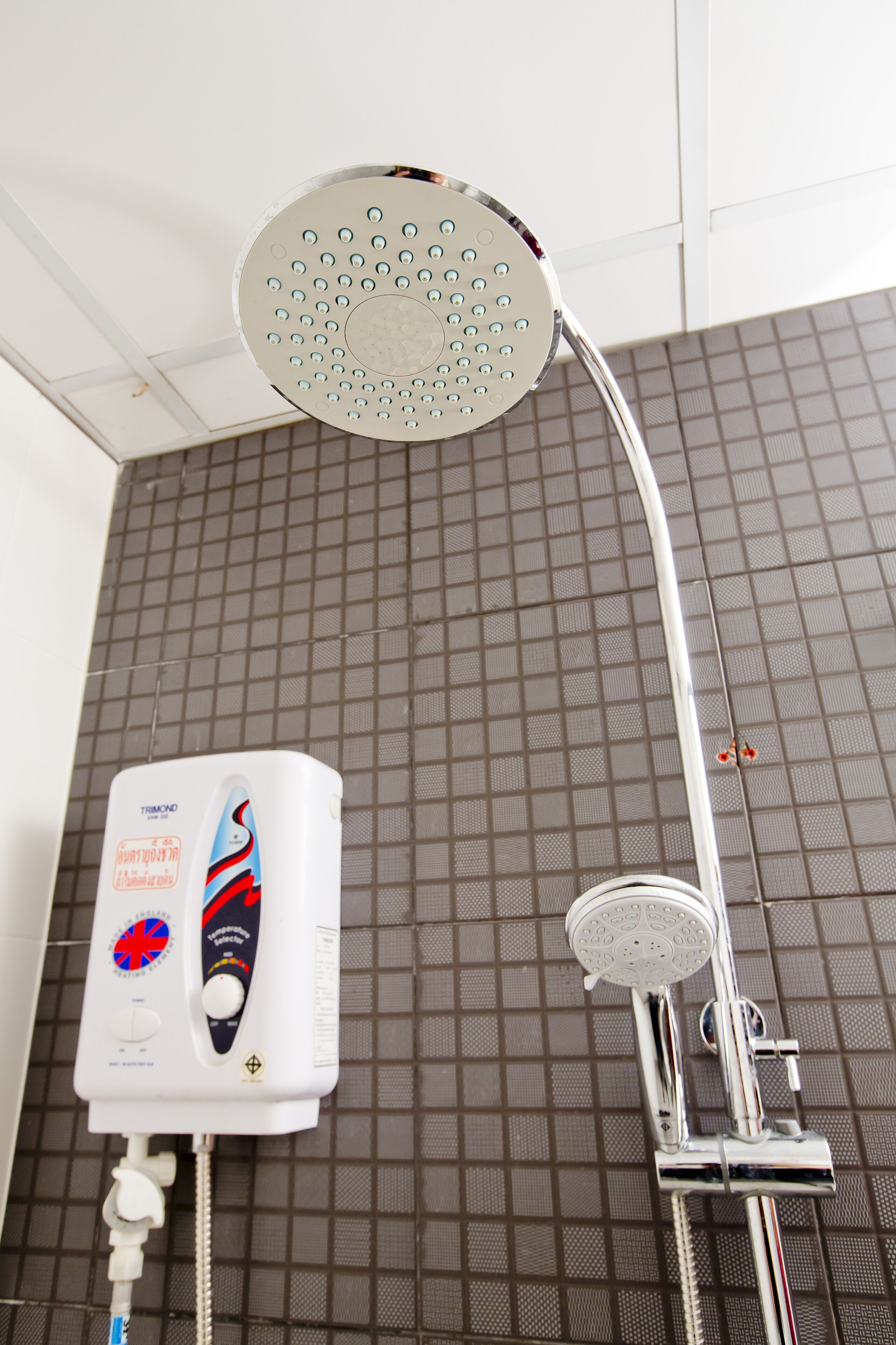 Un pommeau de douche fixé au mur, avec un panneau de commande situé en dessous.