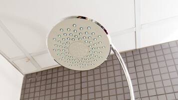 Un pommeau de douche fixé au mur, avec un panneau de commande situé en dessous.