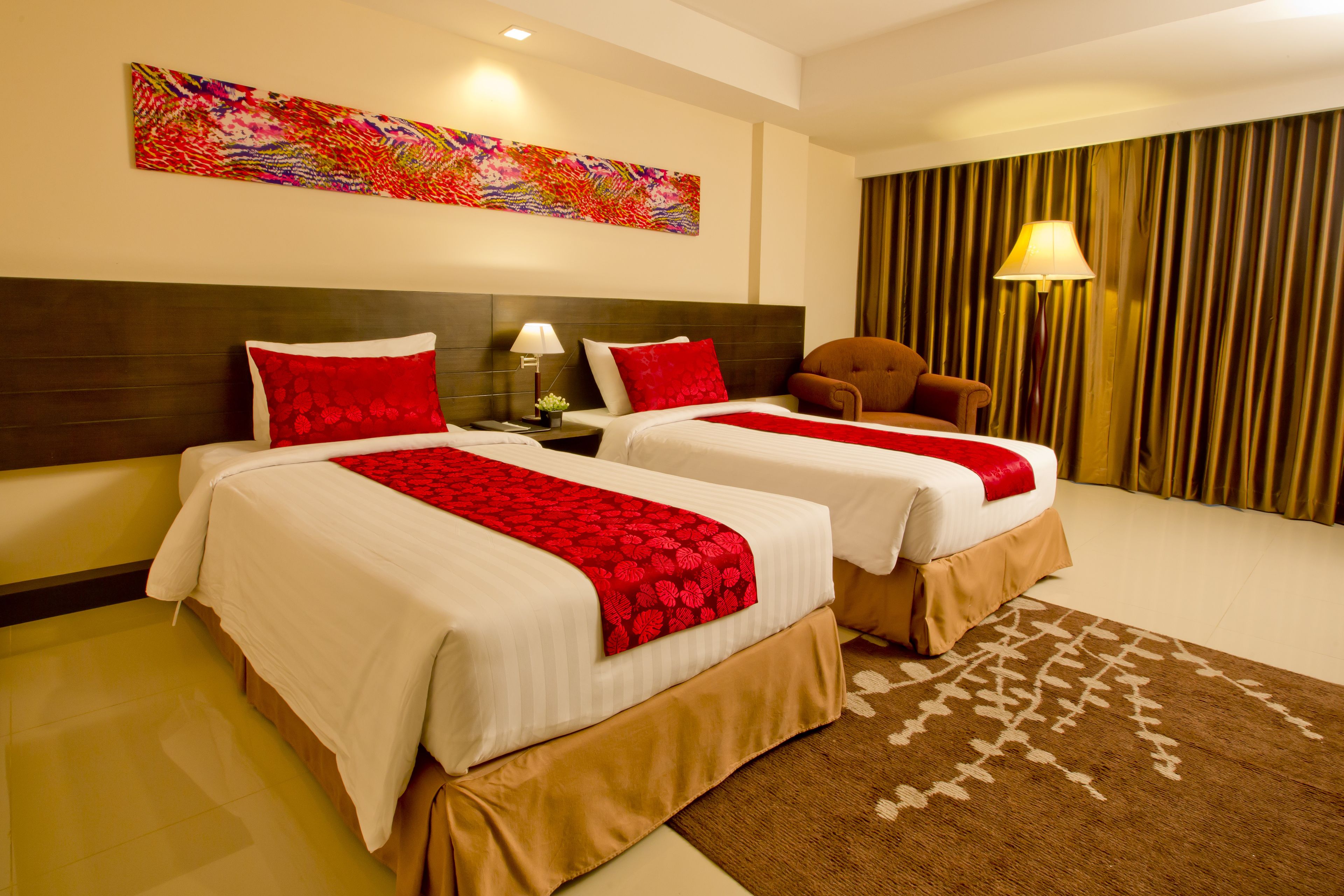 A hotel room with two beds, a large abstract painting, a lamp, and a curtain.