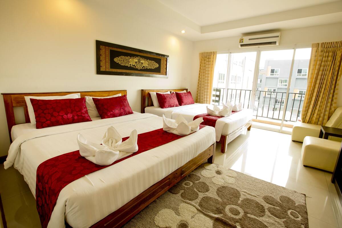 A hotel room with two beds, a balcony, and a view of the city.