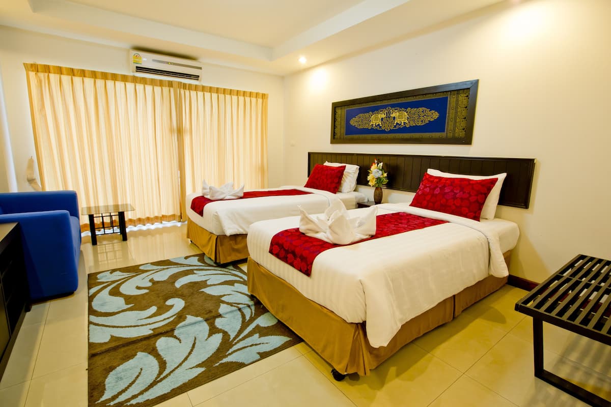 A hotel room with two beds, a desk, and a chair.