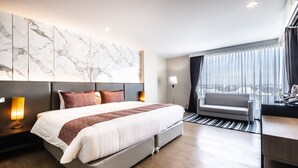 Een moderne hotelkamer met een groot bed, een bank, een bureau en uitzicht op de stad.
