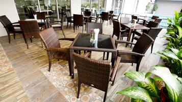 Un patio con mobiliario de mimbre y suelo de baldosas.
