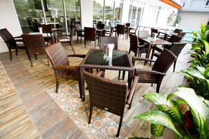 Een terras met rieten meubilair en een betegelde vloer.