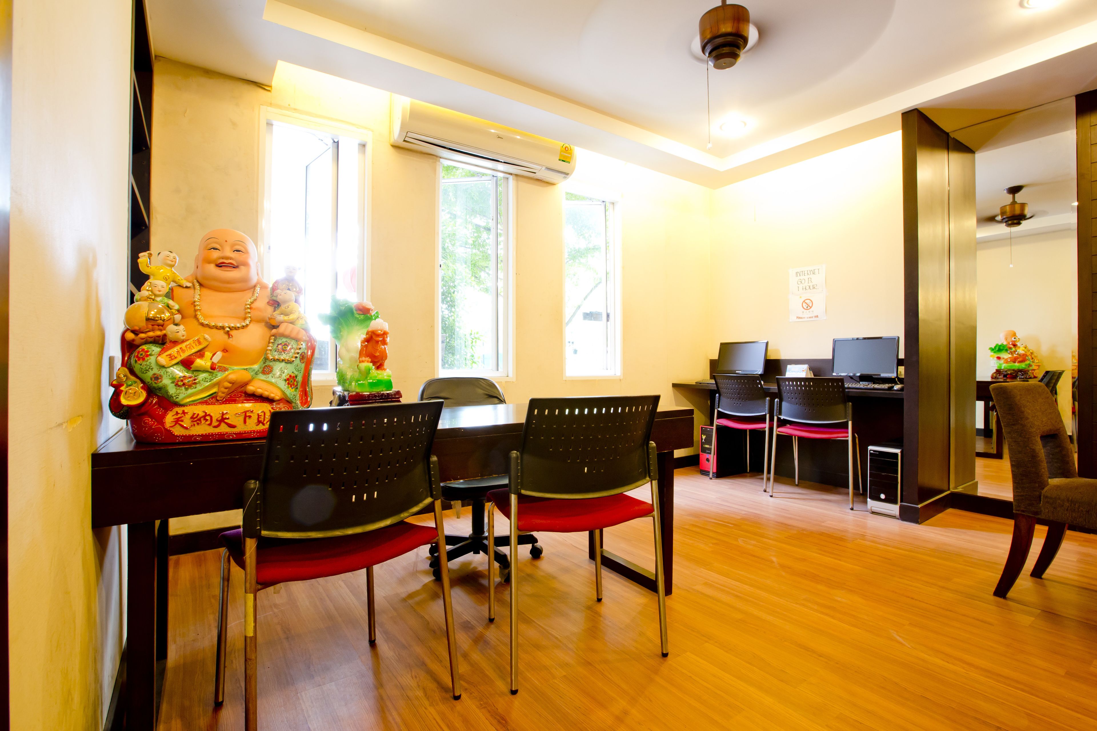 A room with a wooden floor, a desk with a computer, and a statue on the wall.