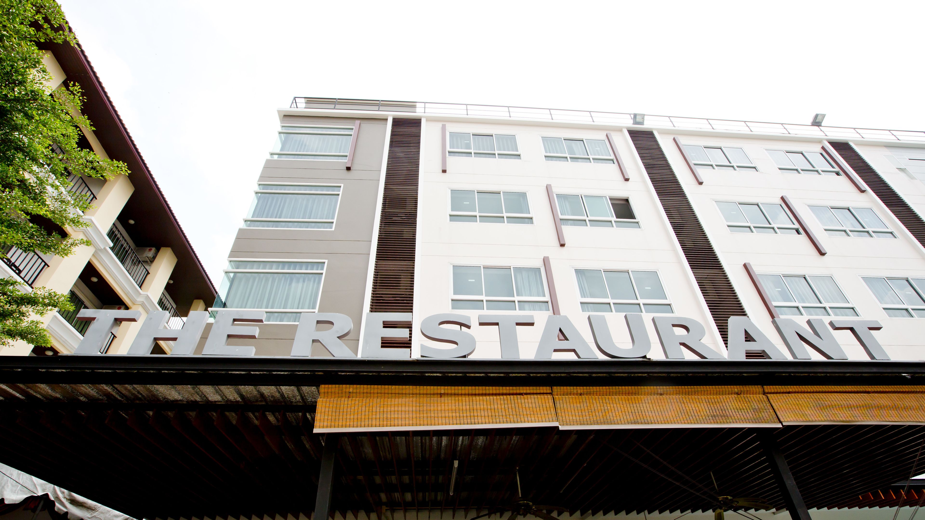Un immeuble à plusieurs étages, avec une enseigne indiquant « LE RESTAURANT » à l’entrée.