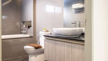 A modern bathroom with a bathtub, toilet, and vanity.