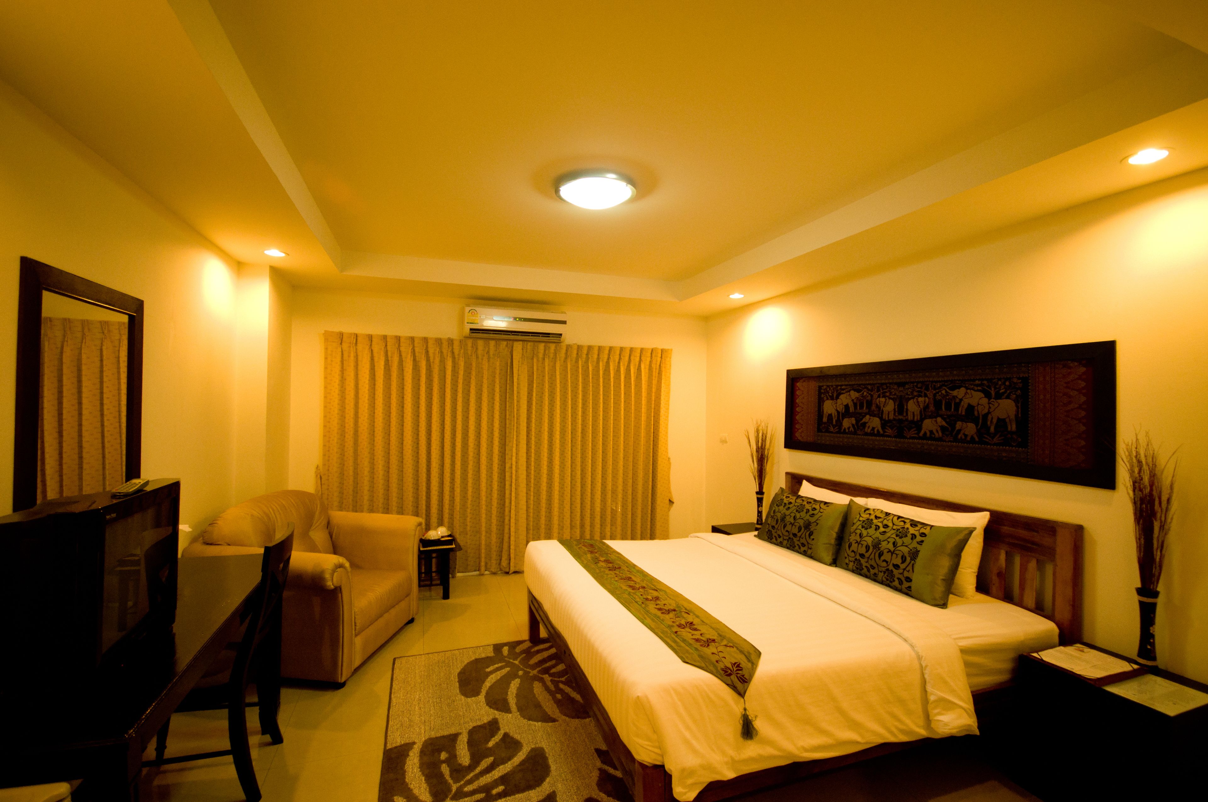 A hotel room with a bed, a sofa, a TV, and an air conditioning unit.