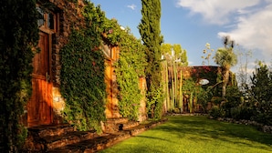 A stone building with a wooden door and steps leading to a well-maintained lawn. - Nirvana Restaurant And Retreat (San Miguel de Allende)