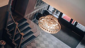 Una escalera de diseño moderno, un candelabro y un suelo a cuadros.